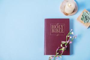 bíblia sagrada cristã com vela sobre fundo azul, configuração plana, vista superior foto
