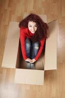 menina sentada em caixa de papelão foto