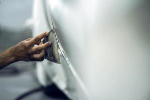 um pintor habilidoso detalhando um primer de pintura de carro profissional enquanto polia um carro branco brilhante, detalhamento de carro, lavagem de carro e reparo de pintura. foco seletivo de imagem cortada foto