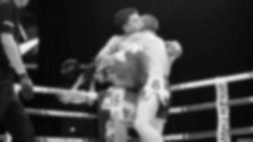 imagens desfocadas estilo de foto em preto e branco de boxe tailandês ou muay thai ou kickboxing, que boxeadores locais e estrangeiros estão lutando no ringue no palco interno como esporte de arte marcial. boxe muay thai