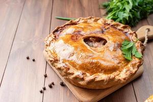 torta de carne caseira com vegetação em fundo de madeira foto