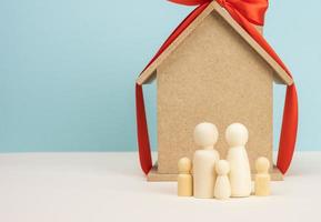 casa de madeira e figuras de família em miniatura, conceito de hipoteca e empréstimo foto