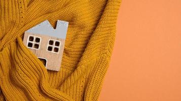 modelo de madeira da casa é envolto em um suéter de malha quente. conceito de empréstimo para isolamento de casas, energia alternativa foto