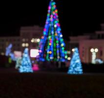 fundo desfocado com uma árvore de natal em uma praça da cidade foto