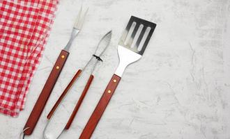 itens de cozinha de metal com alças de madeira para churrasco em fundo branco foto