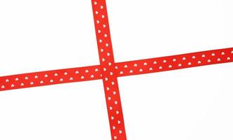 cruz de fita de cetim vermelha para cruzar no fundo branco foto