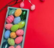 ovos de páscoa multicoloridos decorativos em uma caixa de madeira sobre um fundo vermelho foto