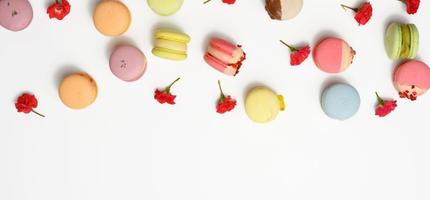 macarons assados com diferentes sabores e botões de rosa em um fundo branco foto