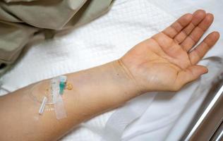 mão feminina dá solução salina na cama no hospital. foto
