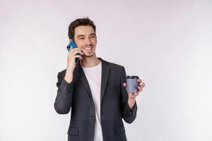 retrato do empresário bonito feliz falando pelo telefone móvel e segurando café quente isolado sobre fundo branco foto