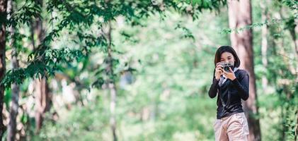jovem mulher bonita usa câmera tirando foto no parque natural