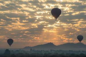 balões de ar quente voando sobre as planícies de bagan durante o nascer do sol na zona de arqueologia de bagan, região de mandalay em myanmar. foto