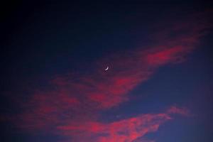 lua crescente e nuvens vermelhas com céu azul foto