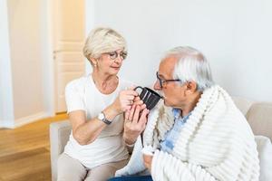 esposa cuidando de seu marido doente. homem sênior com gripe. idosos, homem sênior com doença sazonal de inverno, febre, frio foto