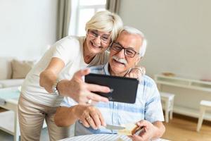 casal sênior tirando uma selfie com tablet. casal de idosos fazendo uma videochamada com amigos ou familiares usando tablet foto