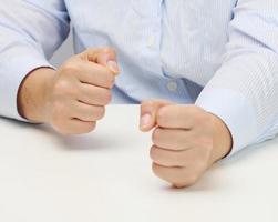 dois fêmea mãos guardada para dentro uma punho em uma branco mesa. rigoroso líder, agressão e pressão em a pessoa foto