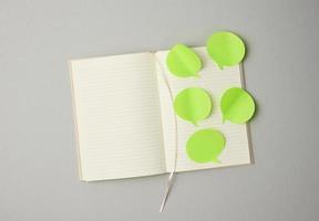 em branco papel verde adesivos dentro a forma do uma nuvem colado para branco folhas do uma caderno, cinzento fundo foto