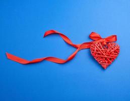 coração decorativo de vime vermelho pendurado na fita de seda foto