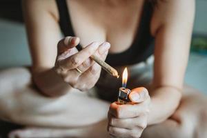 mulheres preparando iluminação acima maconha articulação com isqueiro. cannabis fumante rolando maconha cannabis articulação. drogas narcótico conceito. legal maconha. foto