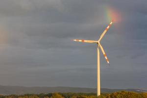 moinho de vento dentro a natureza com uma peça do uma arco Iris foto