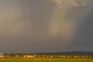 plano panorama com casas e raios solares entre Nuvens de chuva foto