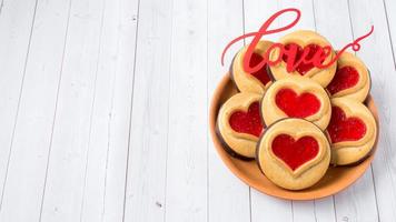 biscoitos caseiros com um coração de geléia vermelha dia dos namorados branco espaço de cópia de fundo de madeira foto