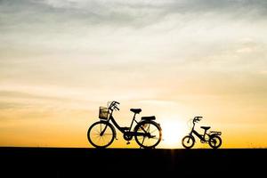 duas bicicletas de silhueta vintage ao pôr do sol foto