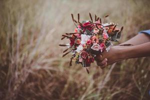 mãos segurando um buquê de rosas vermelhas nas férias de verão foto