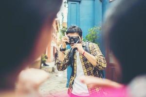 jovem tirando fotos de seus amigos enquanto viajava juntos em uma área urbana