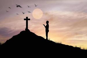 homem silhueta rezando na frente da cruz