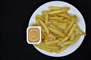 francês fritas em uma branco prato com molho. delicioso velozes Comida. foto