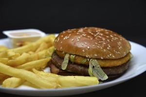 dois hambúrgueres com carne e francês fritas em uma placa. delicioso velozes Comida. hambúrgueres. foto