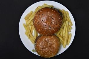 dois hambúrgueres com carne e francês fritas em uma placa. delicioso velozes Comida. hambúrgueres. foto