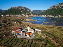 vista aérea do drone da salina na cidade de ston, na croácia. muralhas fortificadas nas colinas ao fundo. campos de sal. obras de sal de pedra. turismo perto do mar adriático. visitas históricas. foto