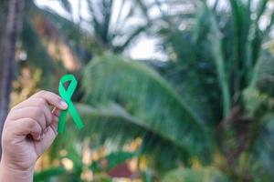 mão segurando uma fita verde. conceito de tratamento de câncer. foto