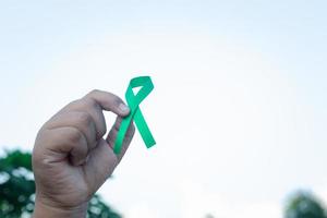 mão segurando uma fita verde. conceito de tratamento de câncer. foto