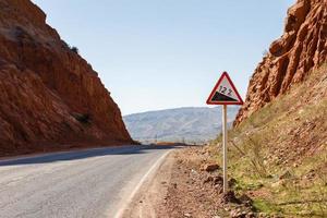 descida estrada placa com percentagem em uma montanha estrada, Atenção tráfego placa Quirguistão foto