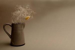 jarro de cerâmica com flores secas em um fundo escuro com espaço de cópia foto