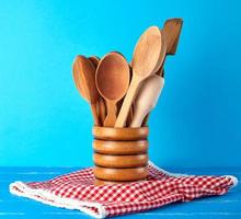 colheres de madeira em um recipiente de madeira em uma mesa azul foto