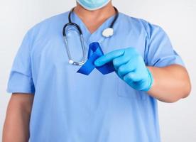 médico dentro azul uniforme e estéril látex luvas detém uma Sombrio azul fita foto