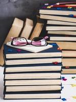 pilha de livros em uma capa azul, óculos rosa em cima foto