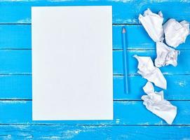em branco branco retangular Folha do papel e amassado peças do papel em uma azul de madeira fundo foto