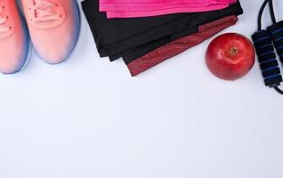 sapatos têxteis rosa e outros itens para fitness em um fundo branco foto