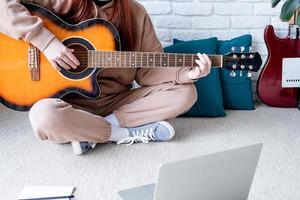 jovem mulher Aprendendo para jogar guitarra às casa foto