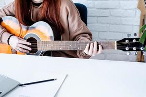 jovem mulher Aprendendo para jogar guitarra às casa foto