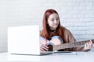 jovem mulher Aprendendo para jogar guitarra às casa foto