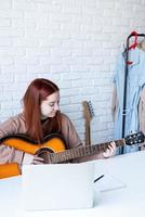 jovem mulher Aprendendo para jogar guitarra às casa foto