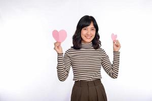 bela jovem asiática segurando um coração de papel em pé contra um fundo branco. bela jovem mulher asiática com coração de papel. foto