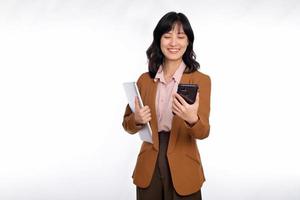 lindo sorridente jovem ásia empresária carregando computador portátil computador e Smartphone para ir enquanto em pé isolado sobre branco fundo foto
