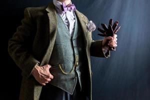 retrato do cavalheiro dentro tweed terno segurando couro luvas. conceito do clássico e excêntrico Inglês cavalheiro. vintage estilo e retro moda. foto